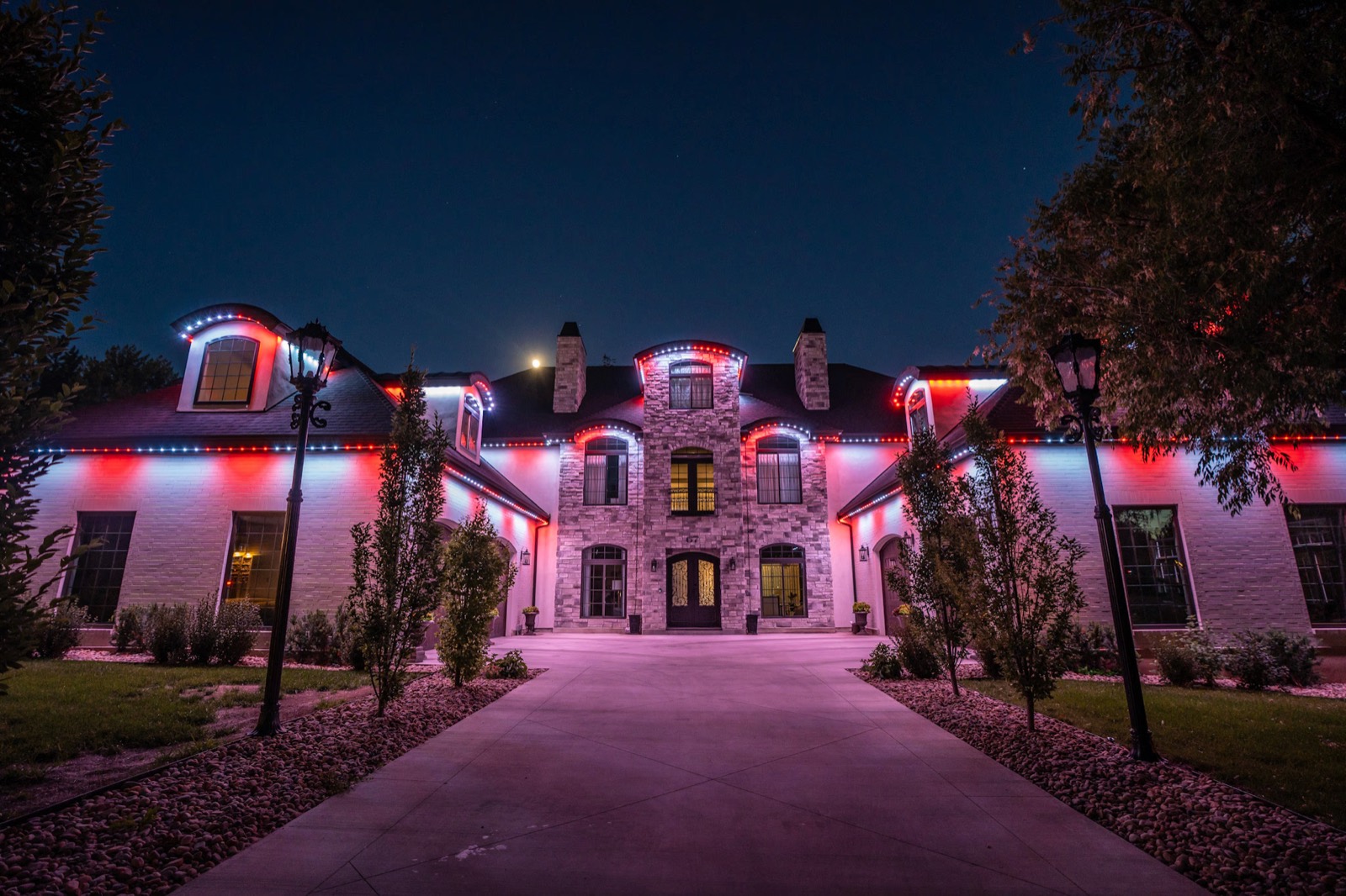 Large stone home lit in red, white and blue along every eave and dormer